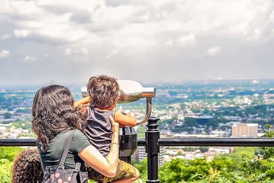 Mother holding child up to telescope viewer at scenic overlook in Montreal