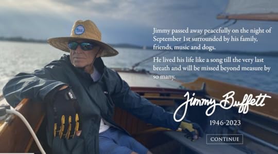 Buffett is shown while steering a sailboat, wearing a hat, jacket and sunglasses, looking to his right, the sea behind him.