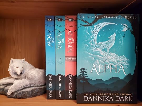 View of the book Spines. Mountain silhouette at bottom and each book is a different color. Wolf statue propping them up