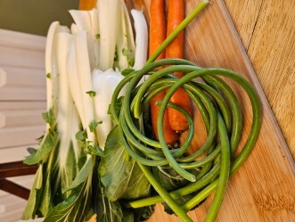 Pak Choi, carrots and garlics scapes on cutting board ready for recipe
