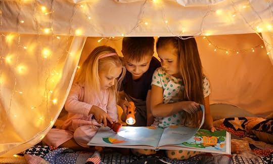 two little girls and little boy in a tent decorated with fairy lights and reading a children's book; how to write a children's book