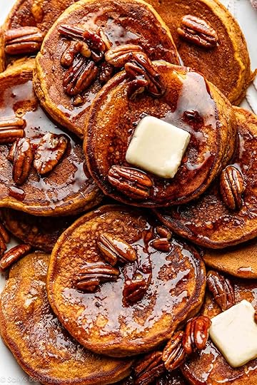 close-up of pumpkin pancakes with slices of butter and maple pecan syrup on top.
