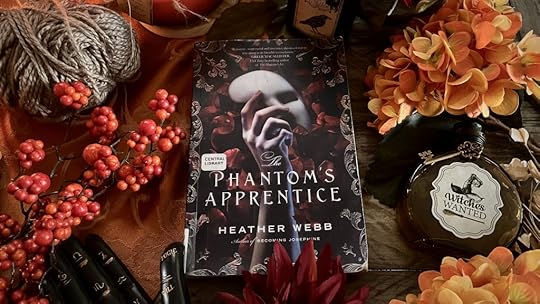 Book The Phantom's Apprentice surrounded by fall flowers and gothic potion bottles