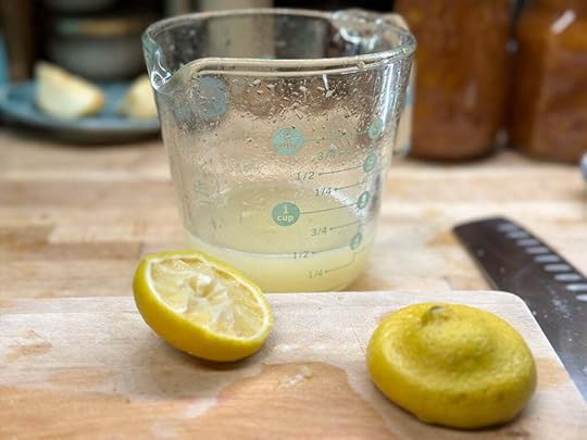 Half a cup of freshly squeezed lemon juice in a glass measuring cup, with hollowed out lemons sitting in the foreground.
