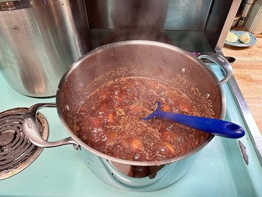 Fig jam in a stainless steel pot, boiling away on a turquoise stove. The same blue spatula from earlier is sticking out of the pot.