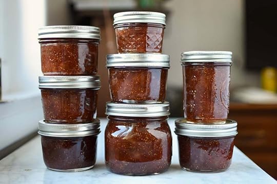 Eight jars of finished fig jam, sitting in three stacks next to a window.