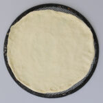 the finished dough on a pizza screen.