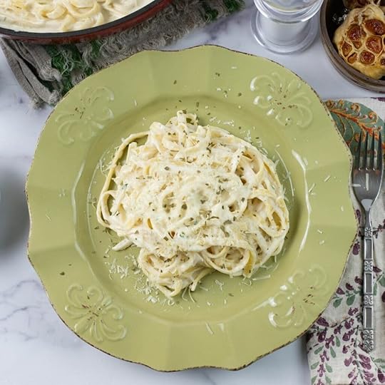 A creamy roasted garlic alfredo served over pasta on a green dinner plate.