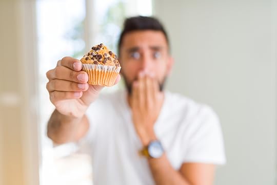 man eating chocolate chips muffin