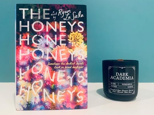 Shown is THE HONEYS (with colorful cover art depicting blossoms and bees) and a Dark Academia candle. Photo by AHS.