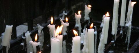 A dozen or so lit white candles with dripping wax against a black background to illustrate Oxford Libraries' Gothic literature quiz!