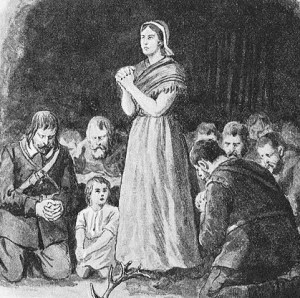 Woman praying with a group surrounding her in a clearing