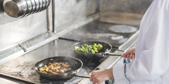 Chef cooking two pans of veggies on a stovetop