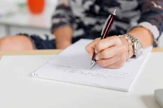 A person writing on a notepad with a pen.
