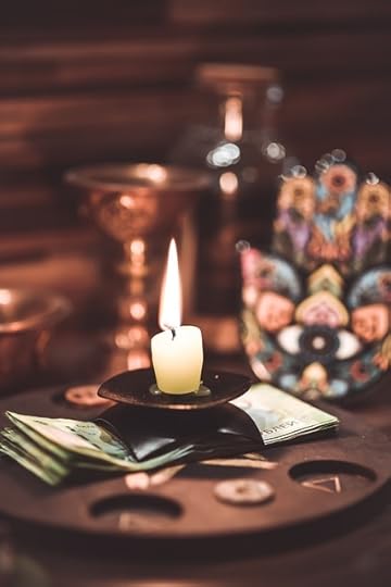 Lit ritual candle on an altar with maskes, photos, and gemstones