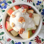 overhead shot of thanksgiving fruit salad topped with greek yogurt and chopped pecans.