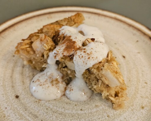 Slice of baked apple oatmeal on a plate with yogurt drizzle