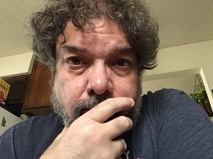 Photo of Jason stroking his beard, no longer wearing glasses.