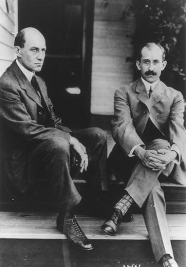 Black and white portrait of Wilbur and Orville, both wearing suits, sitting on the back porch steps of their childhood home. 