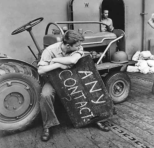 US aircraft carrier deck crewman resting between aircraft landings, off Tarawa, Gilbert Islands, Nov 1943 (US National Archives: 80-G-211064)
