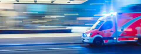 Ambulance with emergency lights flashing driving along a road