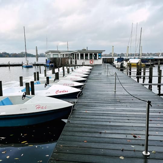 Tretboote an einem verlassenen Steg, Herbstlaub im Wasser, grauer Himmel