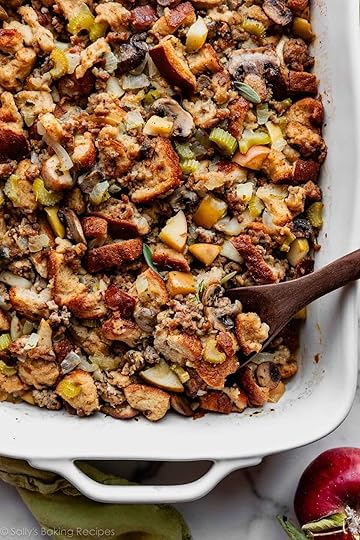 sausage herb Thanksgiving stuffing in a white baking dish with wooden spoon.