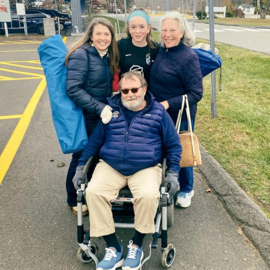 photo of Amy Julia, Marilee, and Amy Julia's mom standing behind Amy Julia's dad, who is using a wheelchair