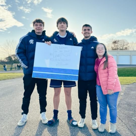 photo of Penny with three high schoolers holding a sign