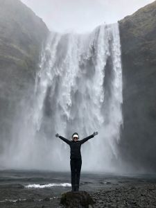 Woman rejoicing at the base of a waterfall