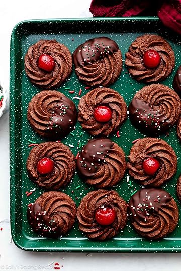 chocolate butter cookies with chocolate and cherries on green baking sheet.