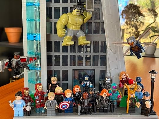 LEGO Marvel minifigs crowded in front of Avengers Tower with Hulk hanging off the front