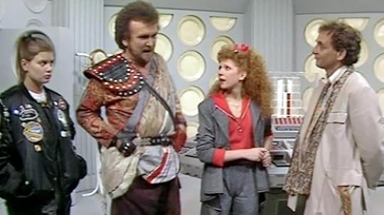 Ace, Glitz, Mel, and the Seventh Doctor stand in the TARDIS control room.