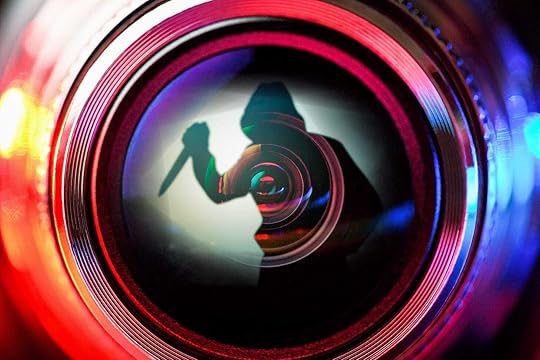 A stylized shot of a security camera lens, which contains a silhouette holding a knife menacingly.