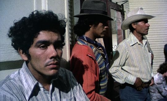 Three Latino men in work clothes look off camera