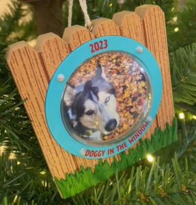 An image of a husky, who doesn't look particularly pleased, is framed in a Christmas ornament.