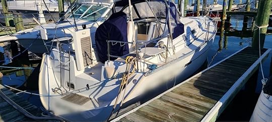 Daytime photo of small yacht at marina dock, showing rear cockpit