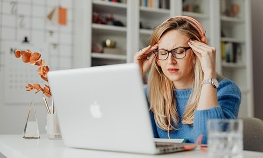 woman sitting in front of laptop with headphones on, looking stressed; Footnotes vs. Endnotes