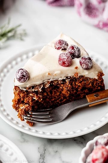slice of gingerbread cake with cream cheese frosting on top and sugared cranberries.