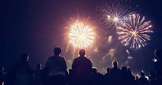 A crowd of people watches New Year's Eve fireworks.