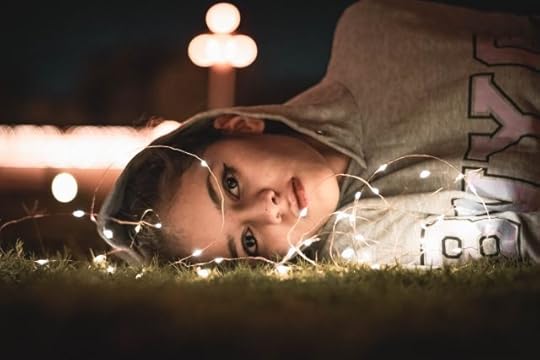 Young woman lying the grass in lights. Why do I feel this way?
