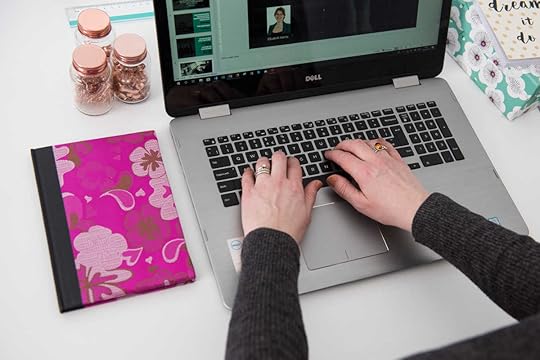 Elizabeth Harrin typing on a laptop next to a pink notebook