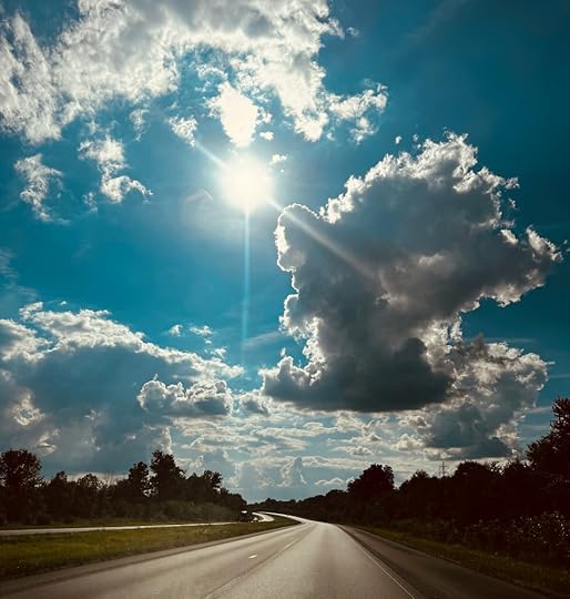 Sun bursting through clouds over roadway