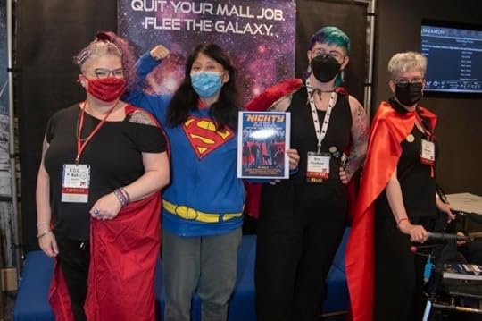 The four superhero authors. Melissa is holding up a photo of the Mighty anthology cover design