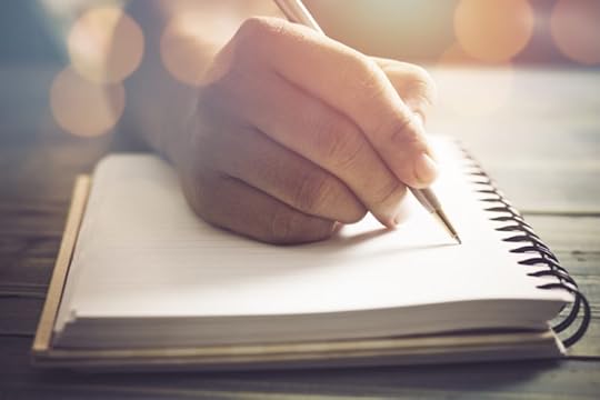 A young hand writes in a spiral notebook