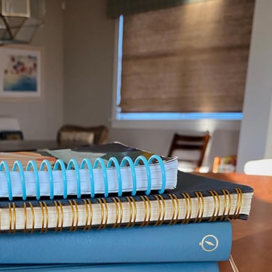 stack of books and spiral bound journals on a table