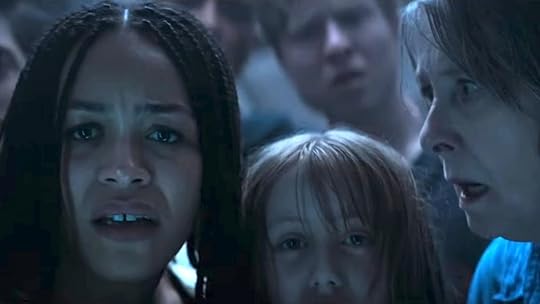 A woman, child, and old woman all look shocked and scared with others behind them in No Way Up