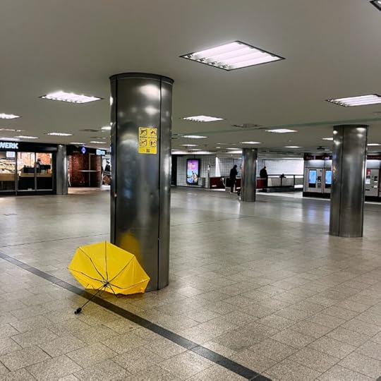 Ein ramponierter gelber Regenschirm liegt im U-Bahn-Bereich des Hauptbahnhofs und formt einen Halbkreis, wie wie aufgehende Sonne