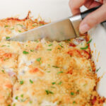 knife cutting into chicken cordon bleu casserole.