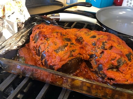 eggplants covered in red sauce and reclined in a glass dish. They are fully cooked, very soft and mushy.